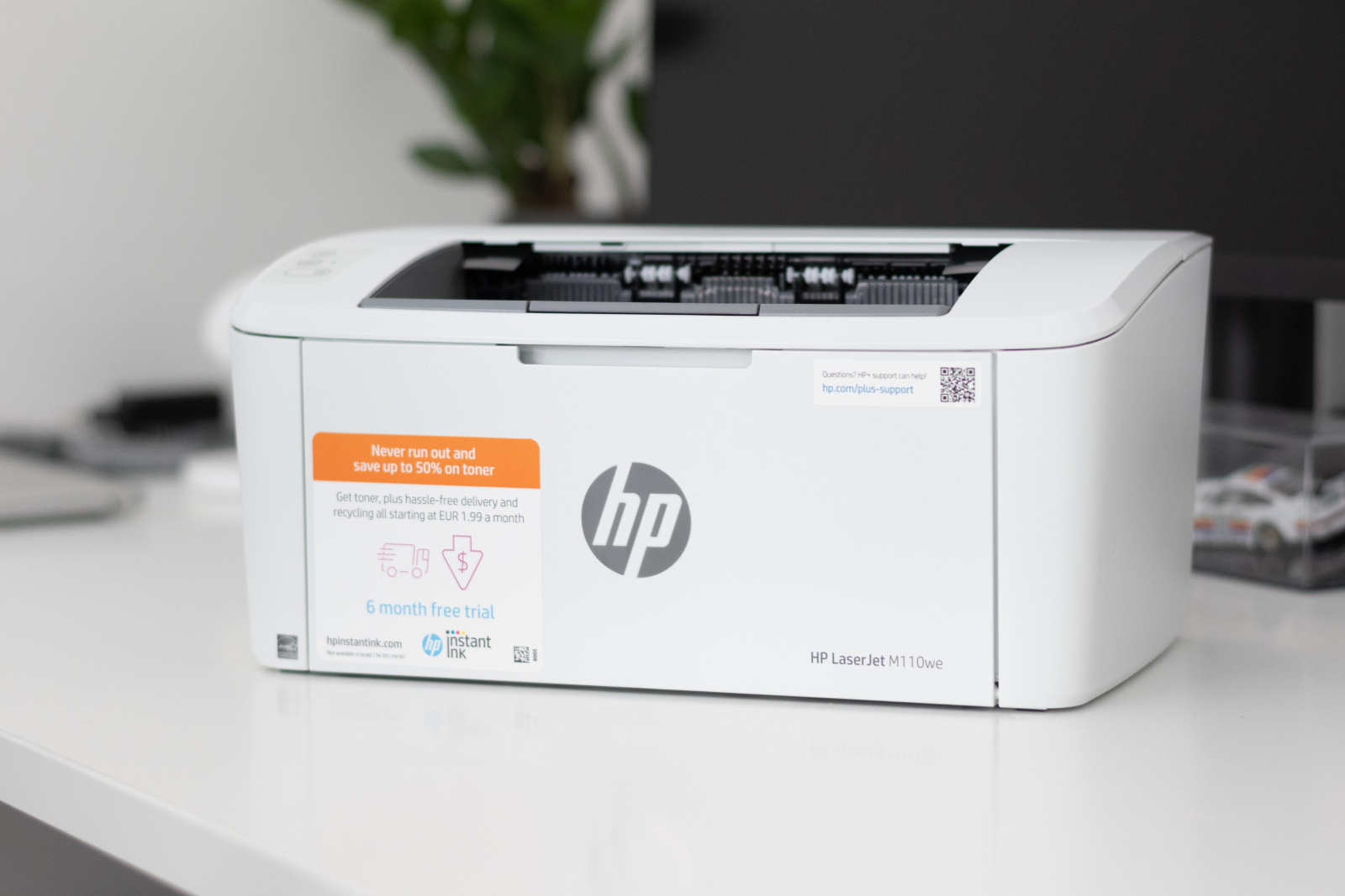 Tiskárna HP LaserJet M110we na kancelářském stole.