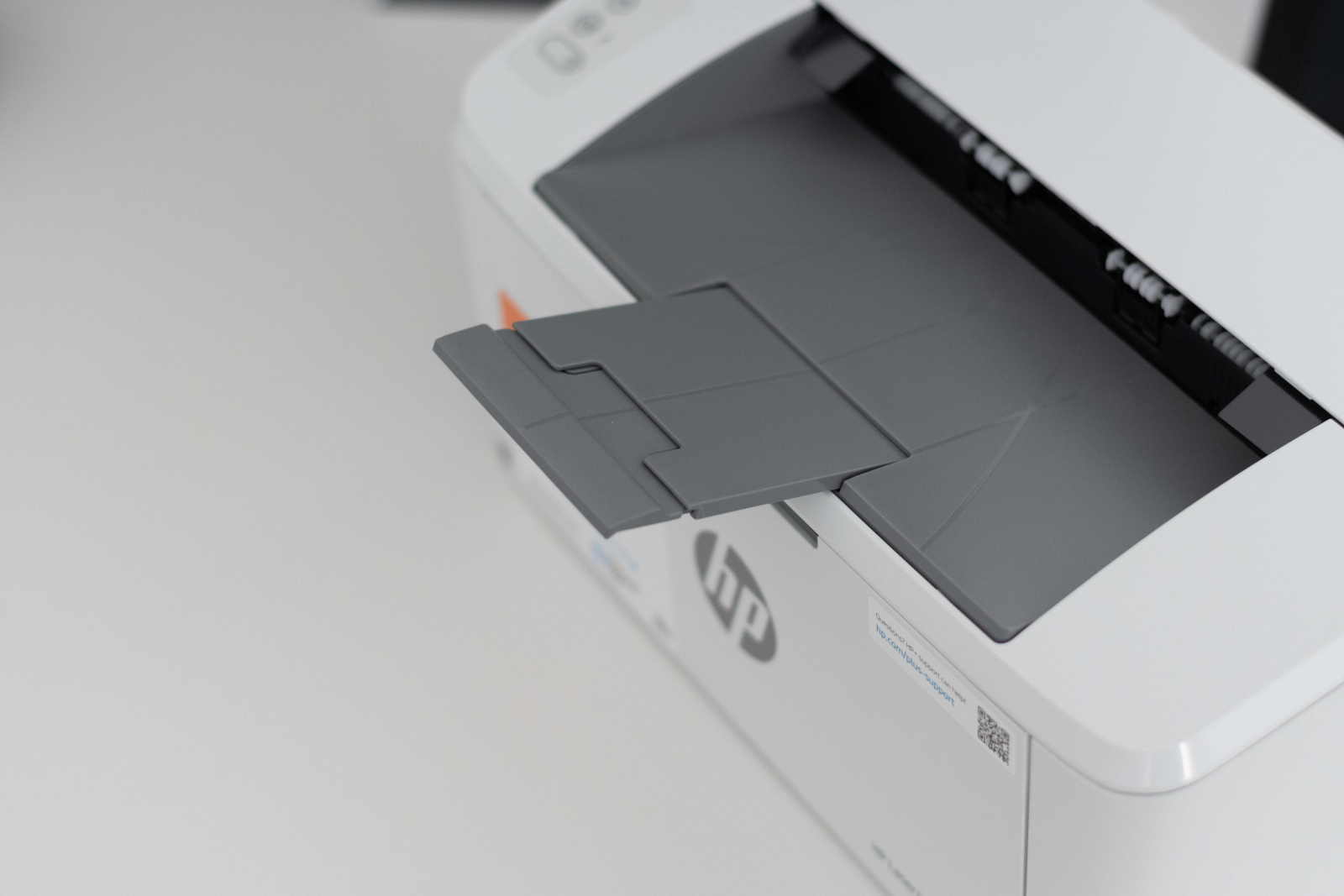 Tiskárna HP LaserJet M110we s vysunutým držákem pro výtisky.